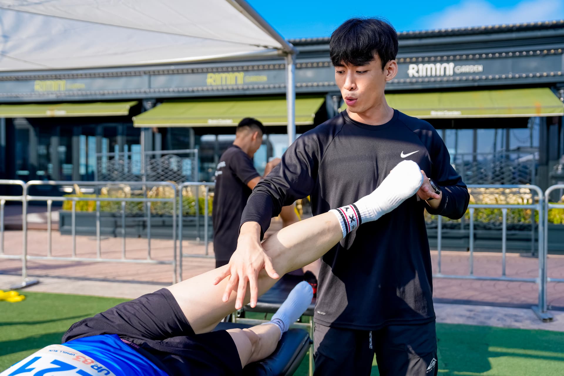 트레이너가 완주자의 다리를 잡아주며 스트레칭을 도와주는 모습