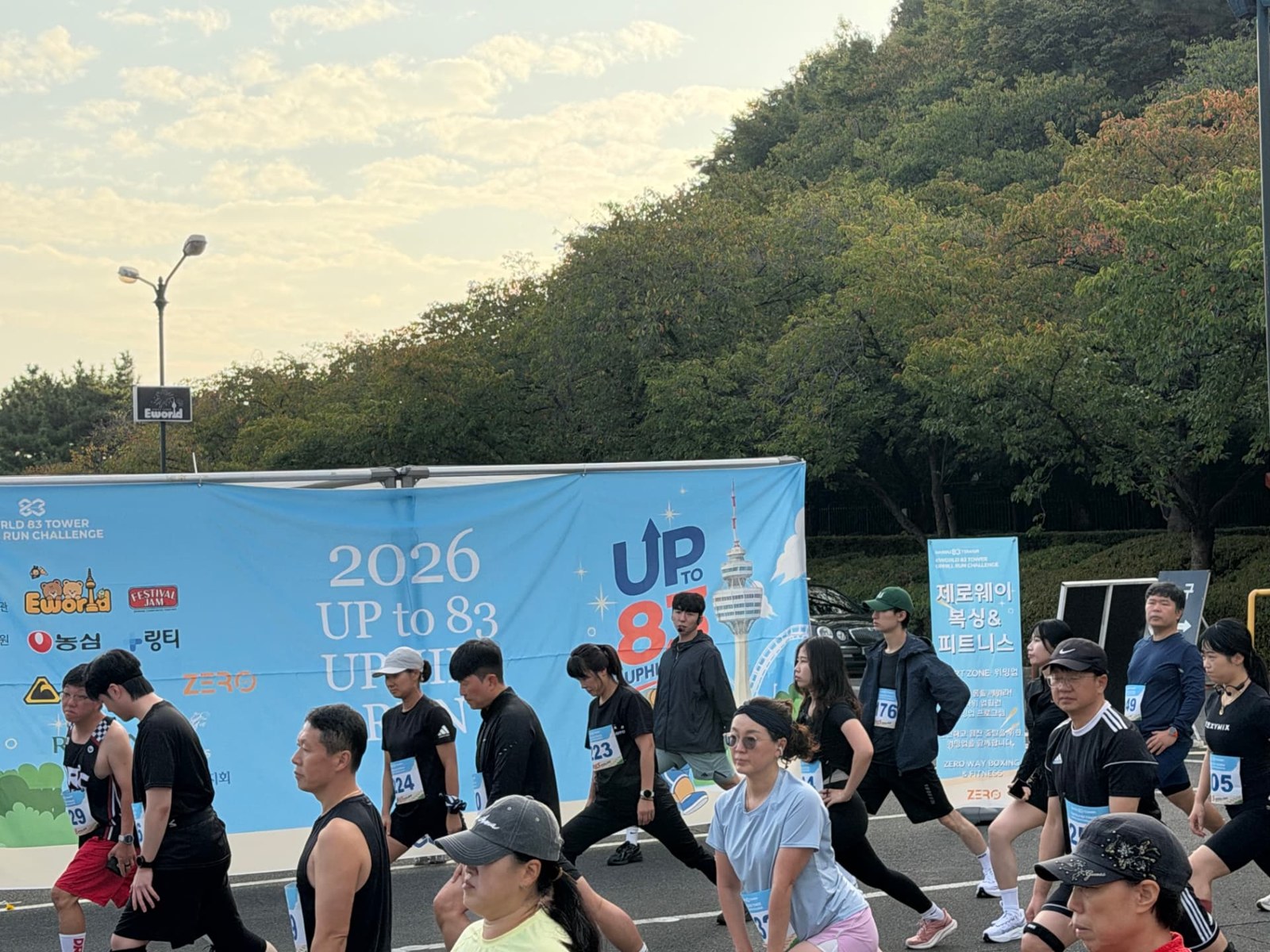 UP TO 83 행사 배너 앞에서 스트레칭하는 참가자들